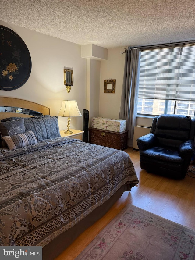 bedroom with a textured ceiling and wood finished floors