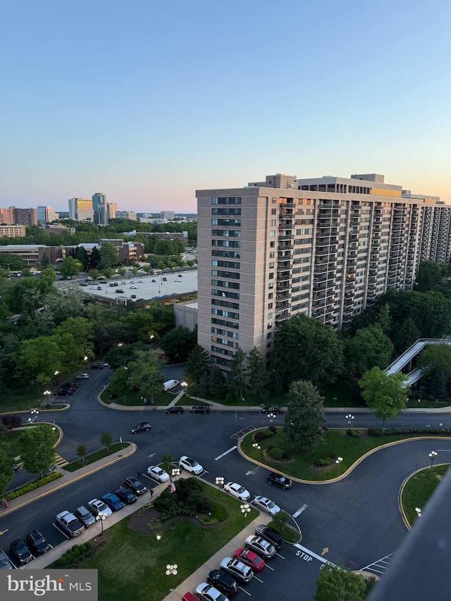 property at dusk with a view of city and uncovered parking