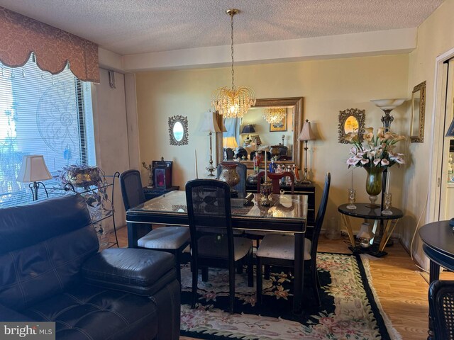 dining room featuring a textured ceiling, a notable chandelier, and wood finished floors