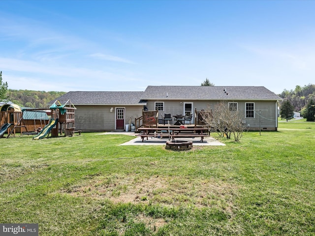 back of property featuring a yard, a patio area, a wooden deck, and a playground