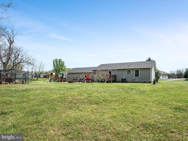 rear view of property featuring a lawn, crawl space, and a playground