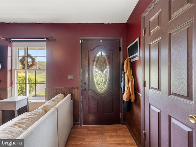 entrance foyer with wainscoting, wood walls, and light wood-type flooring