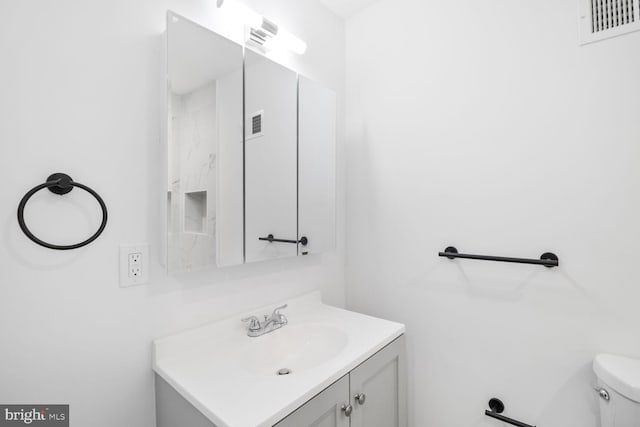 bathroom featuring visible vents, toilet, and vanity