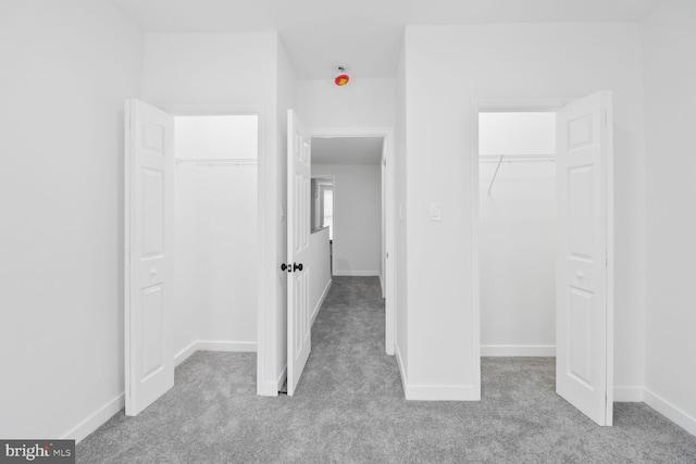 unfurnished bedroom featuring a closet, baseboards, carpet, and a spacious closet