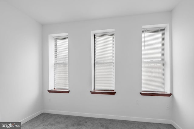 carpeted empty room featuring a healthy amount of sunlight and baseboards