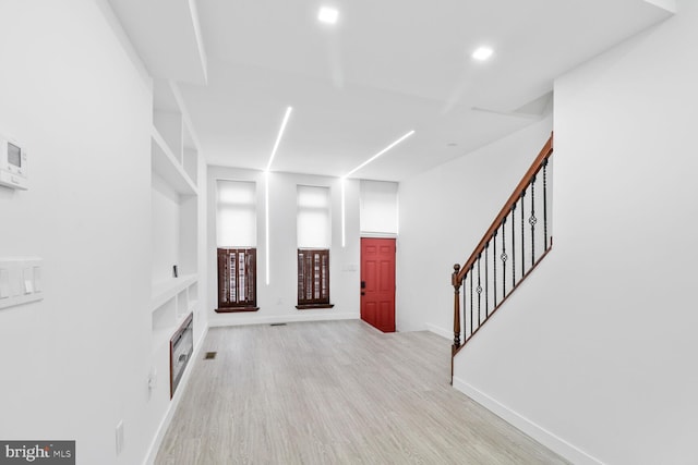 foyer entrance with stairway, baseboards, light wood finished floors, recessed lighting, and a fireplace