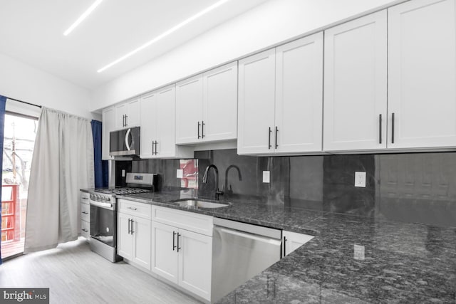 kitchen with dark stone counters, backsplash, appliances with stainless steel finishes, and a sink