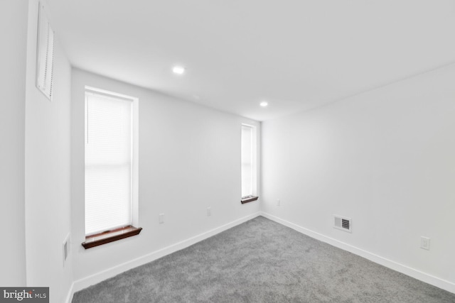 below grade area with a wealth of natural light, carpet flooring, baseboards, and visible vents