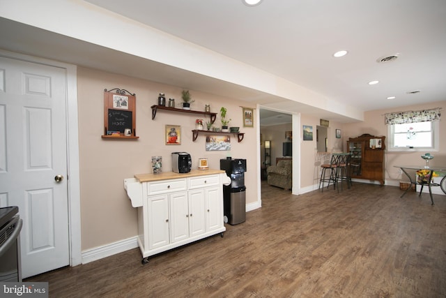 kitchen featuring baseboards, visible vents, white cabinetry, and wood finished floors