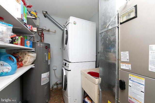 washroom featuring stacked washer / dryer, water heater, and laundry area