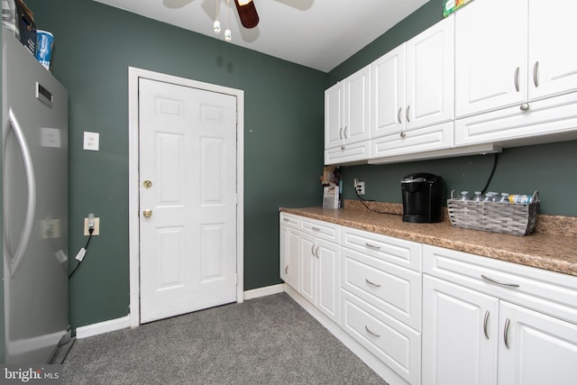 kitchen with carpet, baseboards, ceiling fan, freestanding refrigerator, and white cabinets