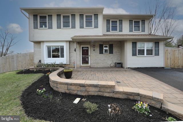 view of front facade with brick siding, fence, and a patio area