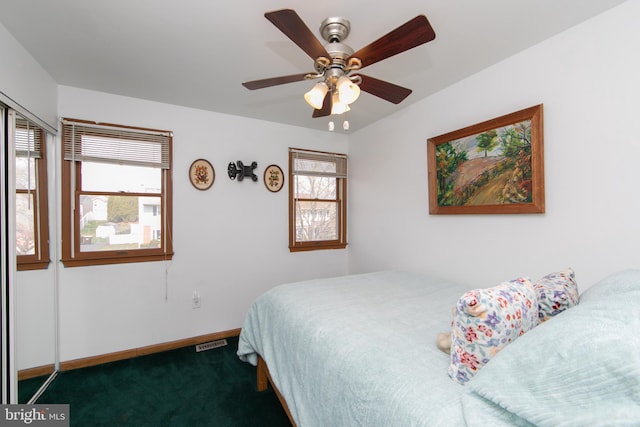 bedroom with baseboards, visible vents, dark colored carpet, and ceiling fan