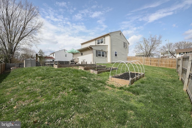back of house featuring an outbuilding, a fenced backyard, a storage unit, a lawn, and a garden