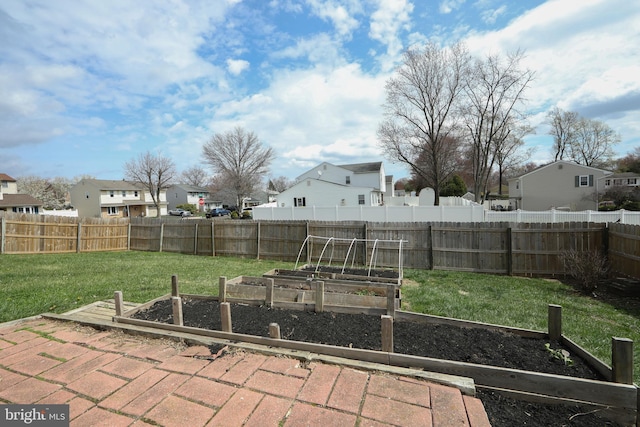 view of yard with a fenced backyard, a vegetable garden, and a residential view