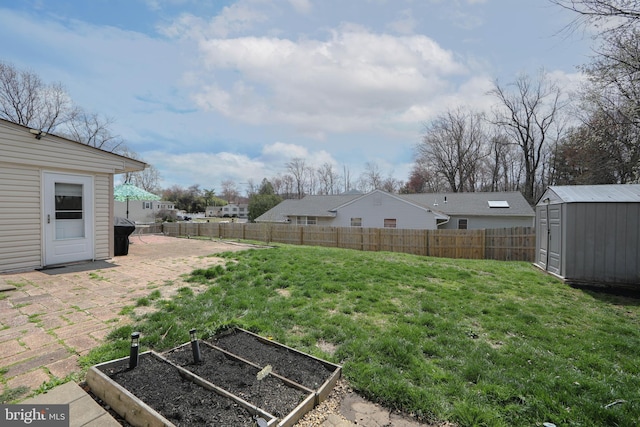 view of yard with a fenced backyard, a vegetable garden, an outbuilding, and a shed