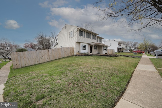 view of front of home featuring brick siding, a front yard, and fence