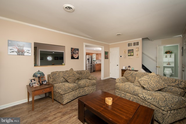 living area with baseboards, stairs, visible vents, and wood finished floors