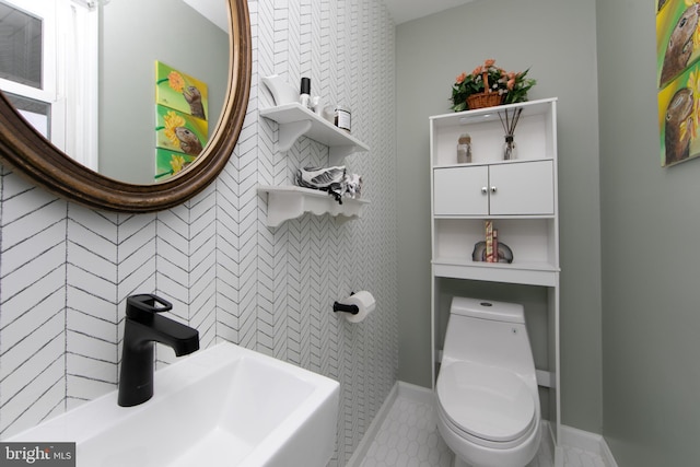 bathroom featuring baseboards, a sink, toilet, and tile patterned floors