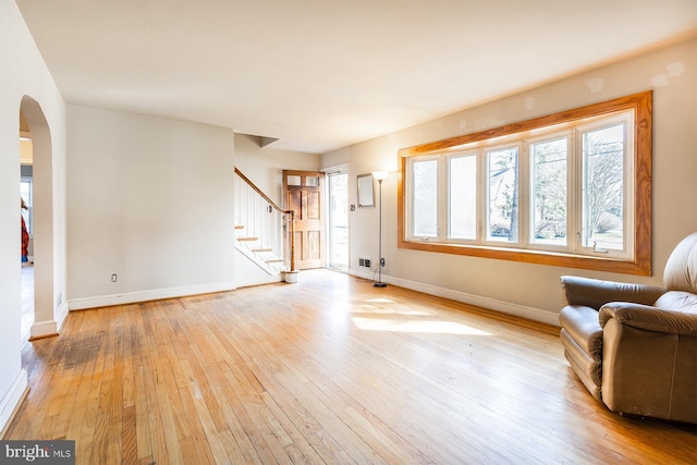 526 Baltimore Annapolis Blvd, Severna Park, MD 21146 - unfurnished living room featuring arched walkways, light wood-style flooring, stairs, and baseboards