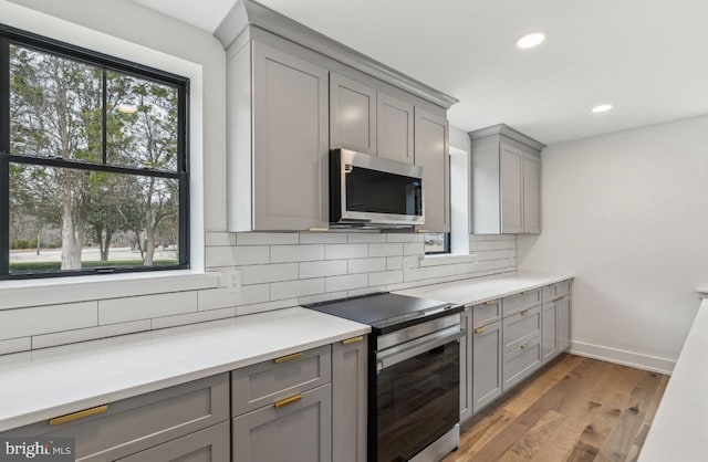 kitchen with tasteful backsplash, gray cabinets, appliances with stainless steel finishes, and a wealth of natural light