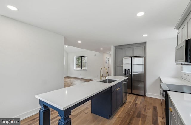 kitchen featuring light countertops, wood finished floors, stainless steel appliances, and a sink