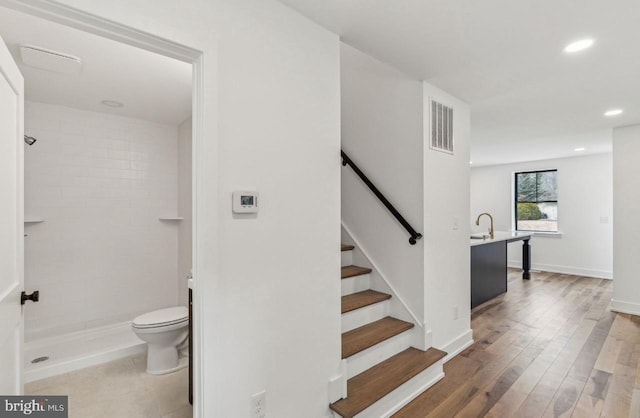 staircase with recessed lighting, visible vents, baseboards, and wood finished floors