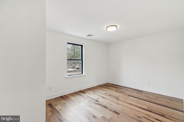 empty room with visible vents, baseboards, and wood finished floors