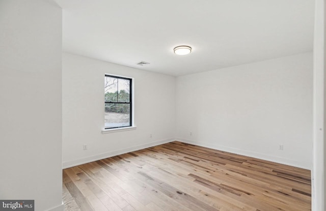 empty room featuring light wood-type flooring, visible vents, and baseboards