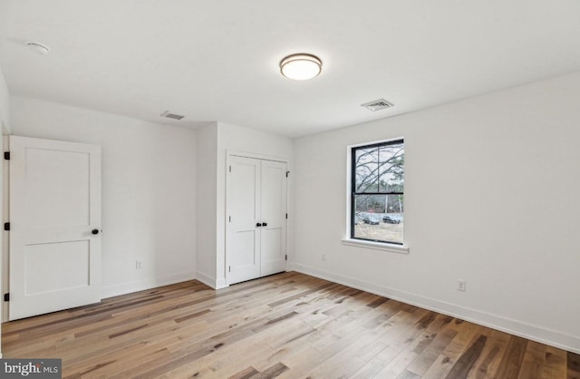 unfurnished bedroom featuring a closet, visible vents, baseboards, and light wood-style floors