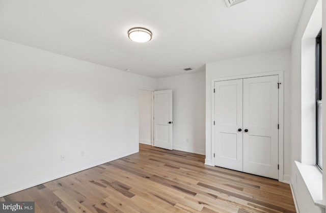 unfurnished bedroom with visible vents, baseboards, a closet, and light wood finished floors