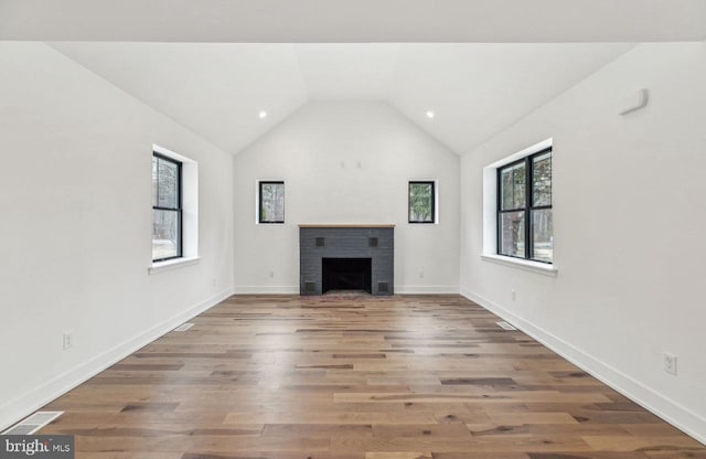 unfurnished living room featuring wood finished floors, baseboards, visible vents, lofted ceiling, and a brick fireplace