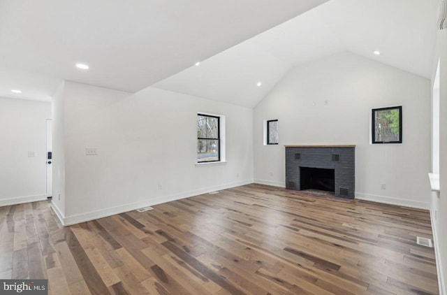 unfurnished living room with a brick fireplace, baseboards, recessed lighting, wood finished floors, and high vaulted ceiling