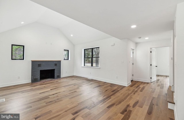 unfurnished living room featuring light wood-style flooring, a fireplace, baseboards, and vaulted ceiling