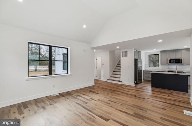 unfurnished living room with light wood-style flooring, visible vents, plenty of natural light, and stairs