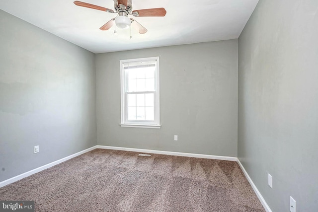 carpeted empty room with ceiling fan, visible vents, and baseboards