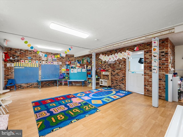4137 Hedgesville Rd, Hedgesville, WV 25427 - playroom with wood finished floors, a textured ceiling, and brick wall