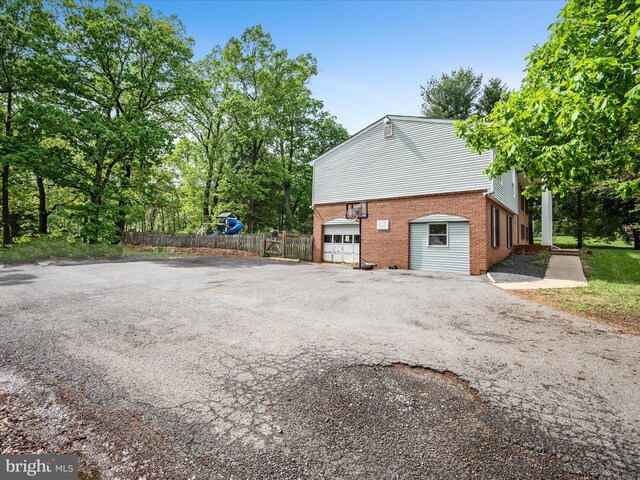 4137 Hedgesville Rd, Hedgesville, WV 25427 - view of side of property featuring asphalt driveway, brick siding, fence, and an attached garage