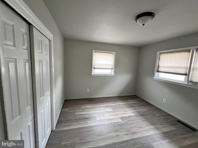 unfurnished bedroom with a closet, baseboards, visible vents, and wood finished floors