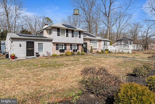 view of front of property with a front yard, roof mounted solar panels, and a chimney