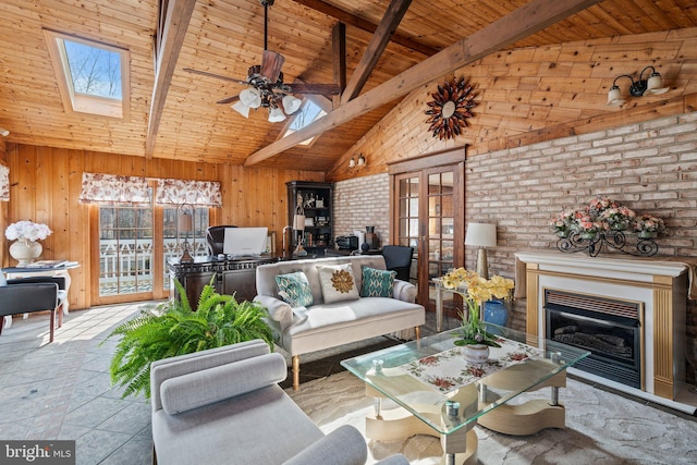 living area featuring wood walls, vaulted ceiling with skylight, french doors, wooden ceiling, and a ceiling fan