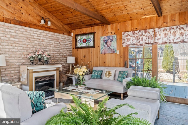 living area with vaulted ceiling with beams, wood walls, wood ceiling, and a glass covered fireplace