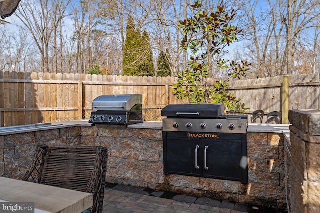 view of patio featuring area for grilling, a fenced backyard, and exterior kitchen