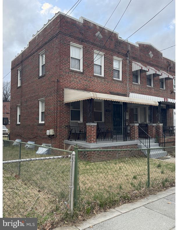 multi unit property featuring a fenced front yard, brick siding, and a front yard