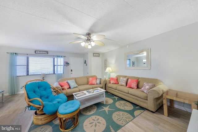 living area featuring a ceiling fan, wood finished floors, baseboards, and a textured ceiling