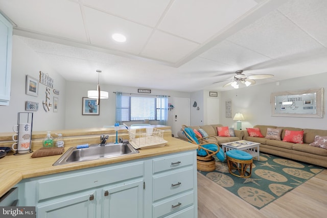 kitchen featuring a ceiling fan, wood finished floors, open floor plan, and a sink