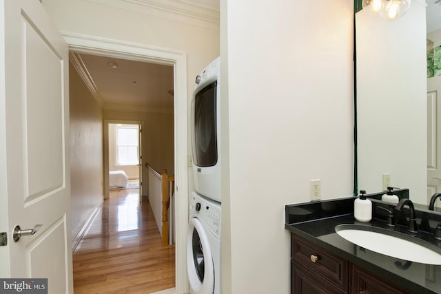 1210 R St NW Unit 313, Washington, DC 20009 - laundry area featuring stacked washer / drying machine, ornamental molding, and light wood-style floors