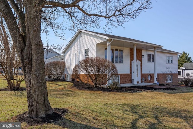 raised ranch featuring brick siding and a front yard