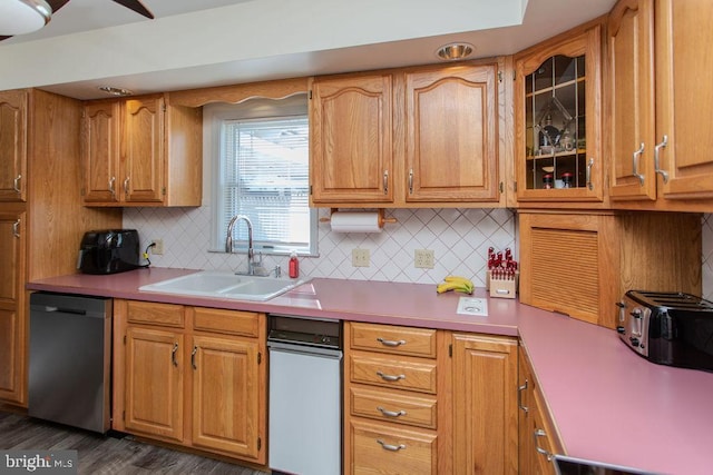 kitchen with stainless steel dishwasher, light countertops, glass insert cabinets, and a sink