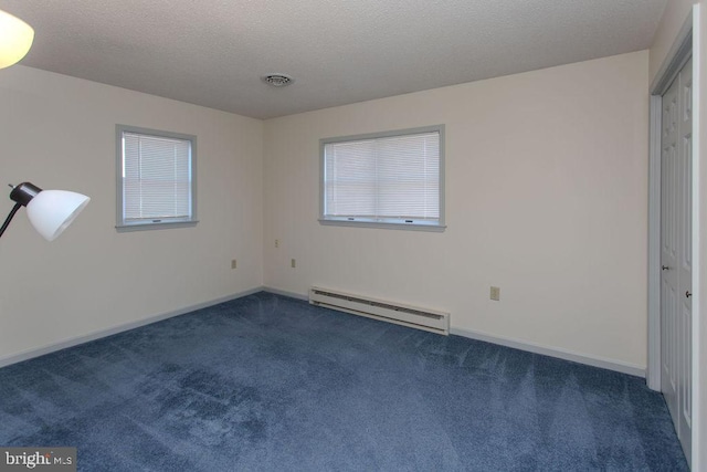 spare room with dark colored carpet, a baseboard radiator, a textured ceiling, and visible vents